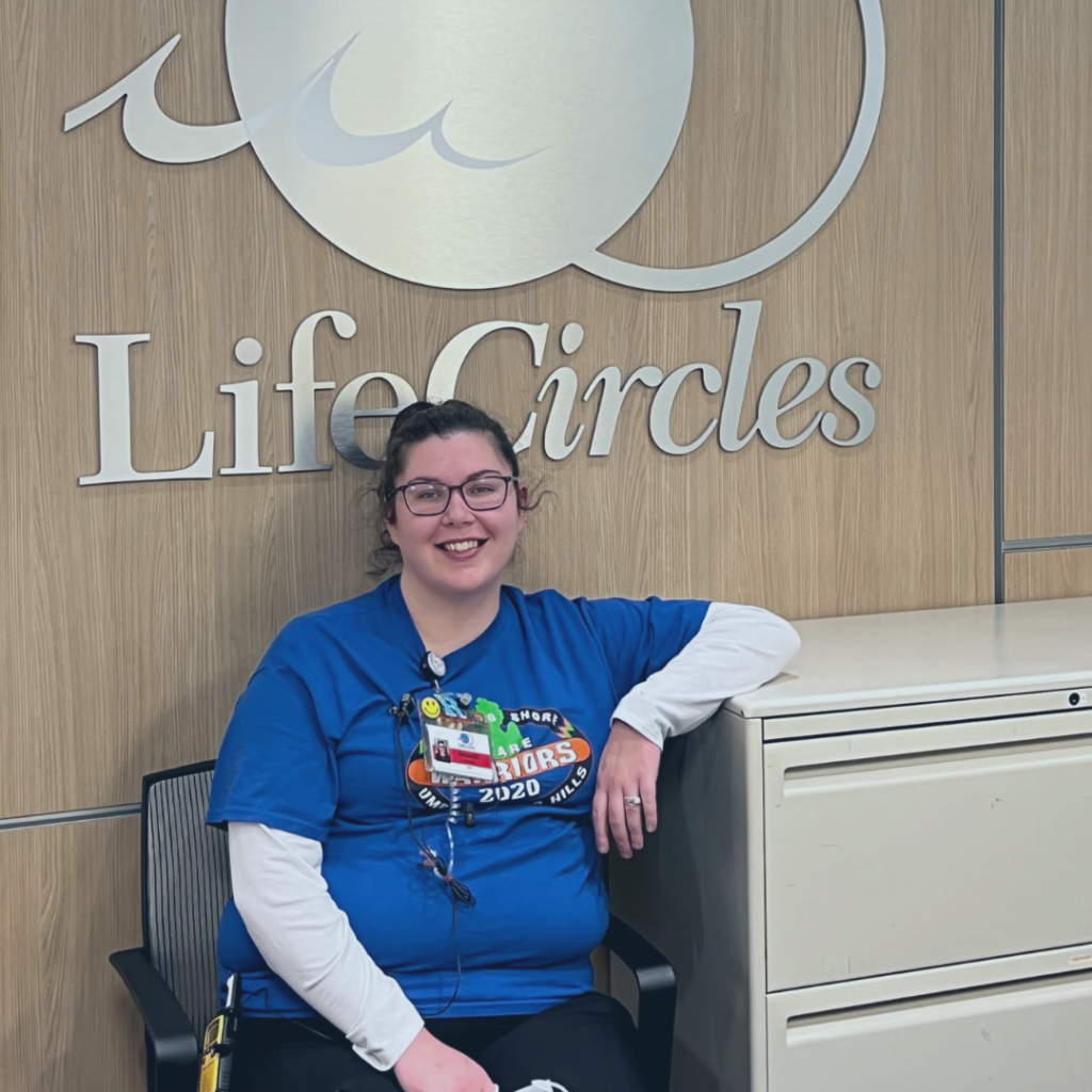 Amanda Stanfield, sits in a chair in front of a LifeCircles logo. 