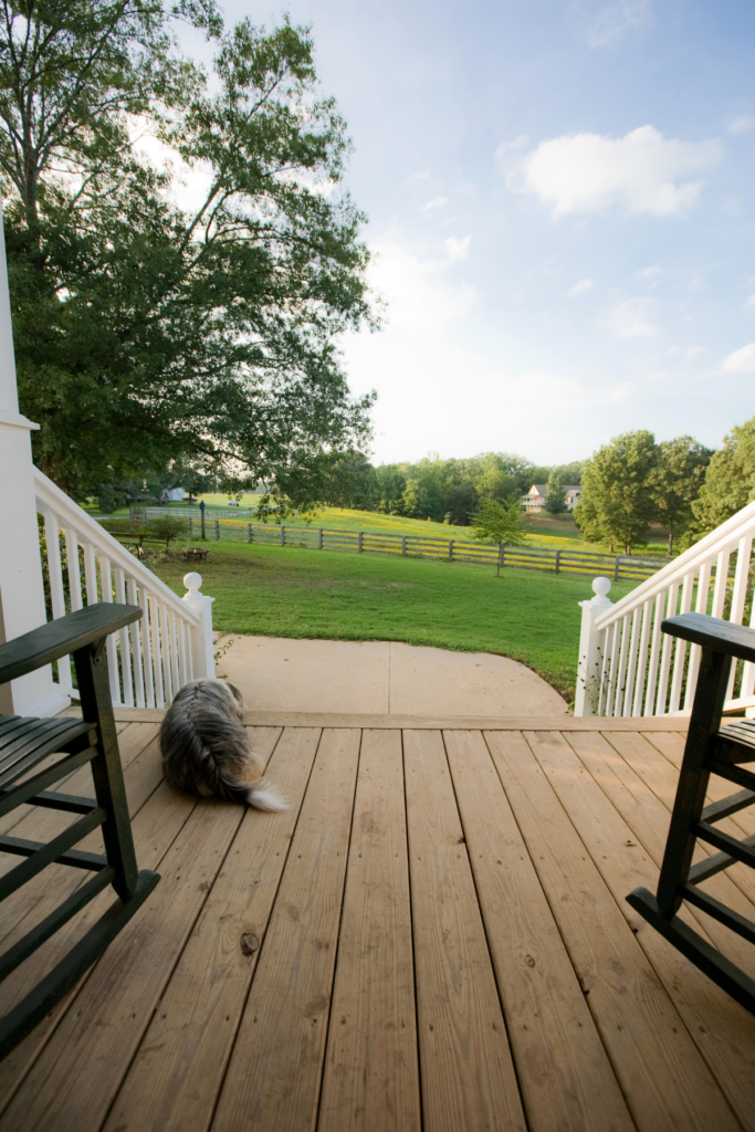 A view of green grass and an open field from a porch. 